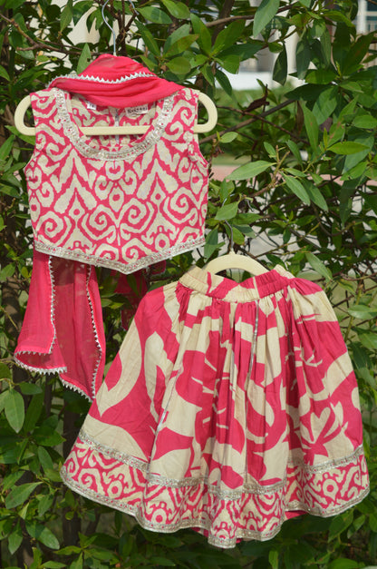 Pink and white patterned fabric items hanging on a branch with green leaves in the background