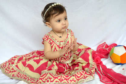Baby in a red and beige traditional outfit with a colorful ball on a white background