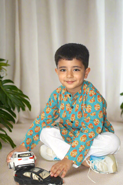 Child in a floral kurta playing with toy cars on a light-colored floor.