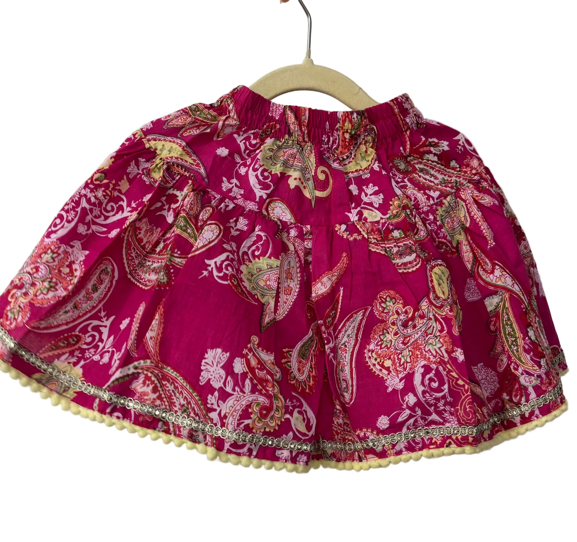 Pink paisley patterned skirt on a hanger against a white background