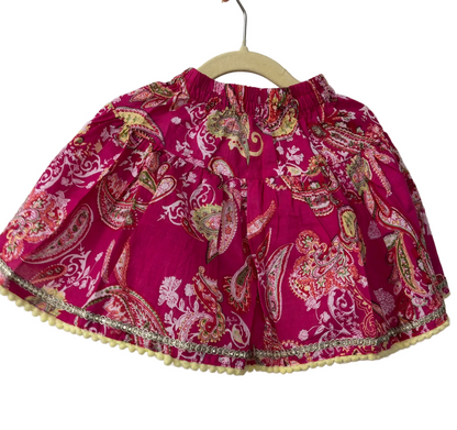 Pink paisley patterned skirt on a hanger against a white background