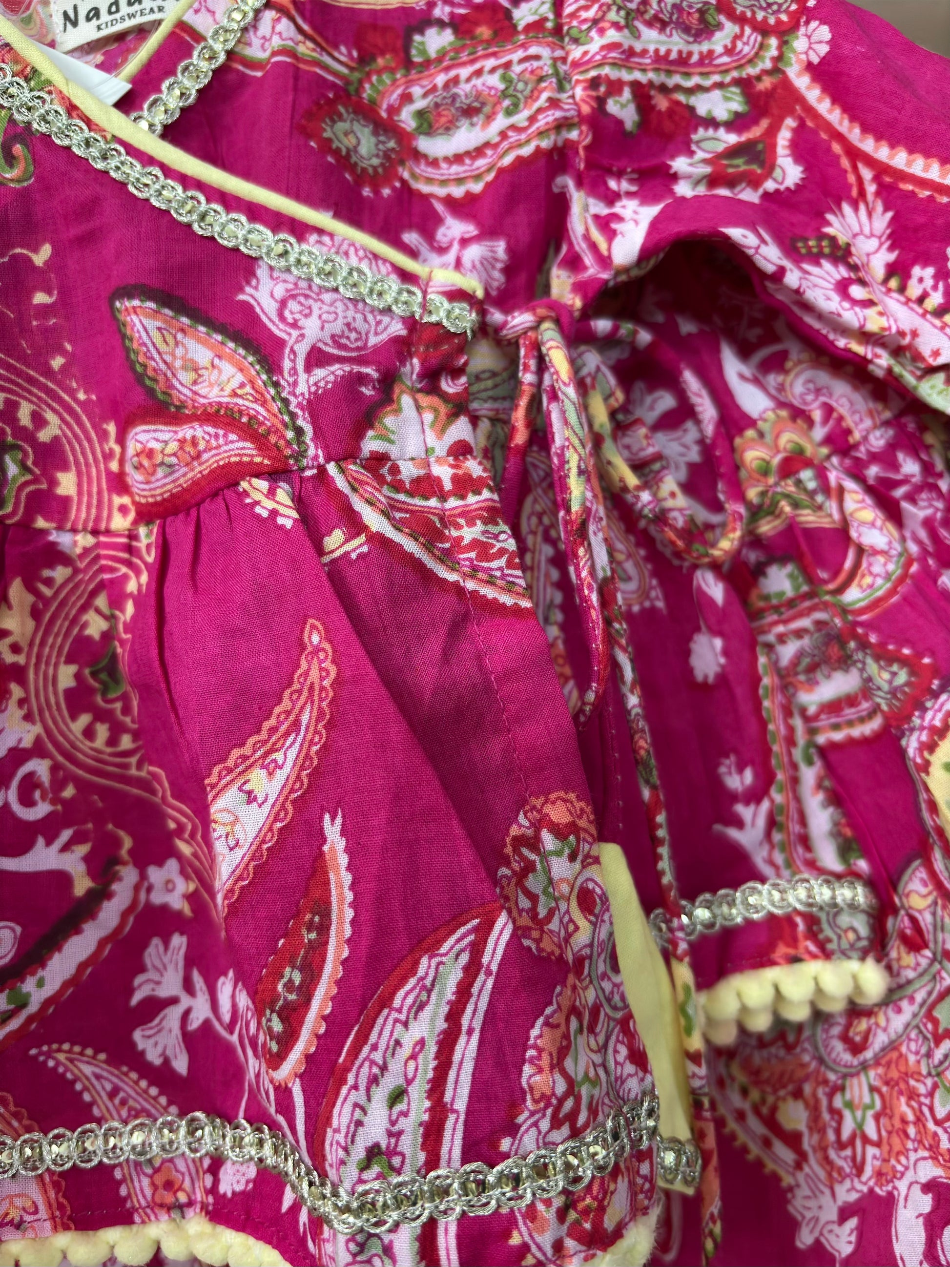 Close-up of a pink patterned garment with decorative elements.