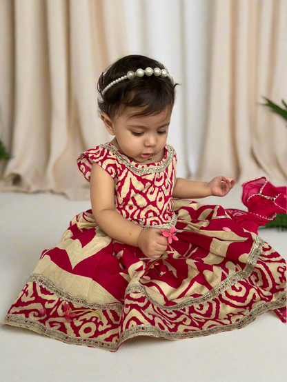 Child wearing a red and beige traditional outfit on a white background